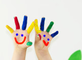 Bunt bemalte Kinderhände mit lachenden Gesichtern
