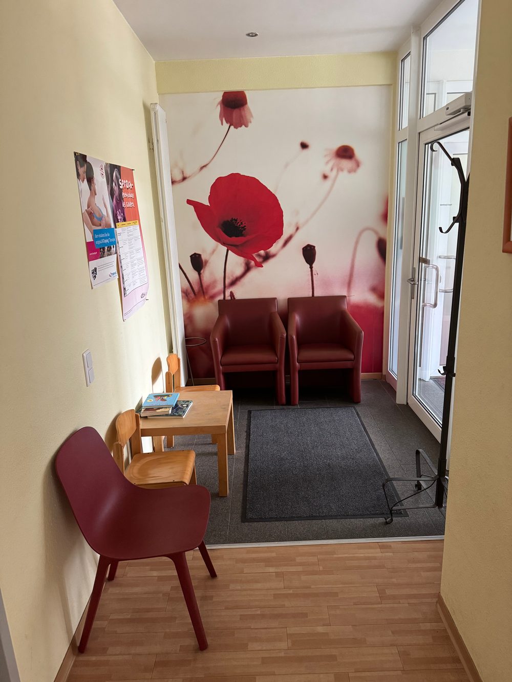 Wartebereich der Praxis mit Sitzgelegenheiten und Mohnblumenwand